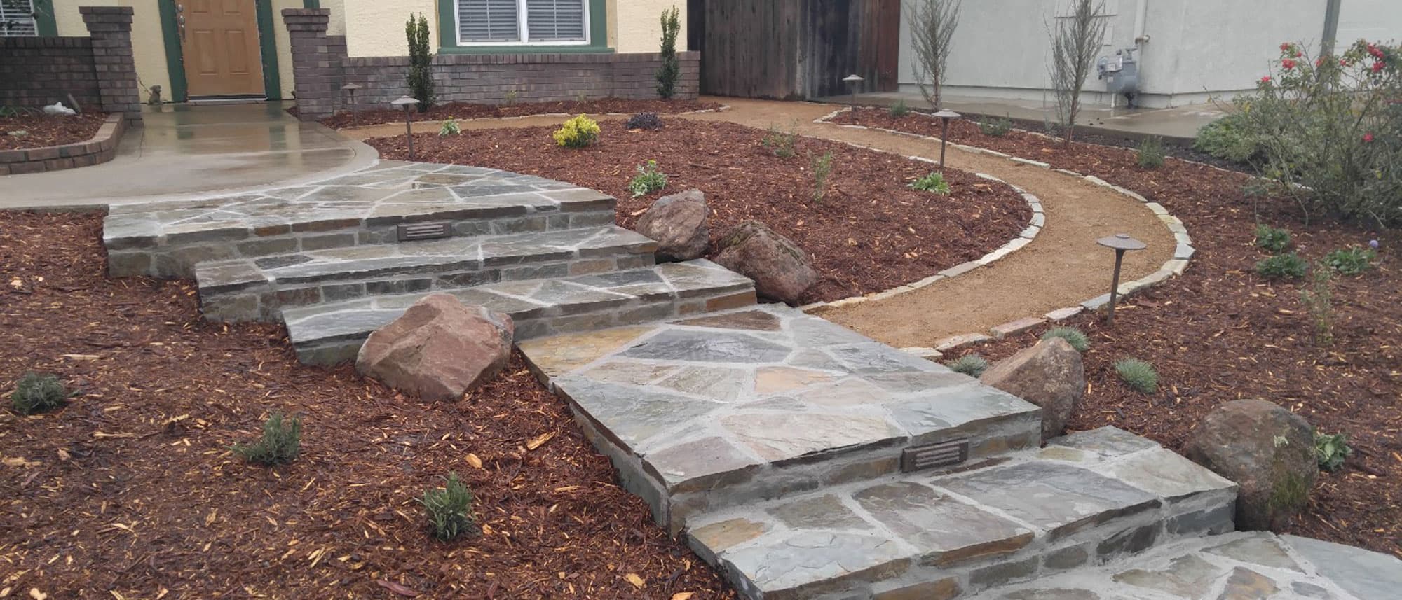 Flagstone entry steps and walkway with landscape lighting and a decomposed granite path