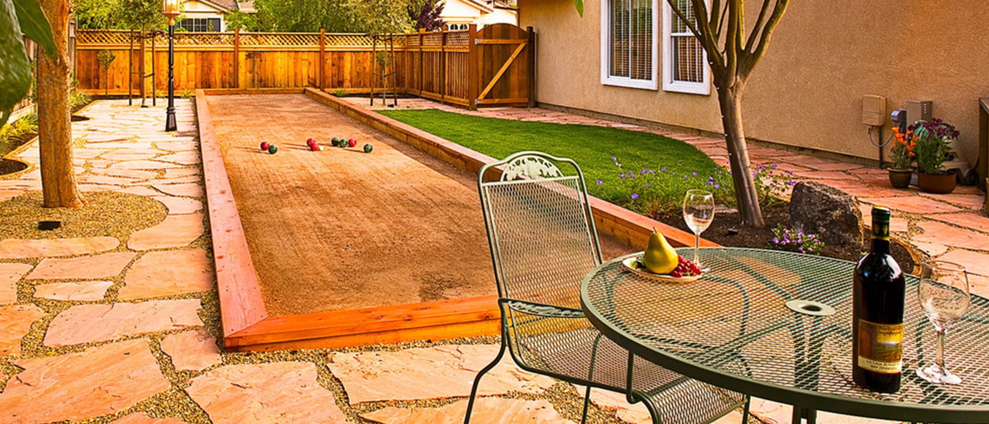 Backyard bocce ball court bordered by a flagstone patio and an artificial turf lawn